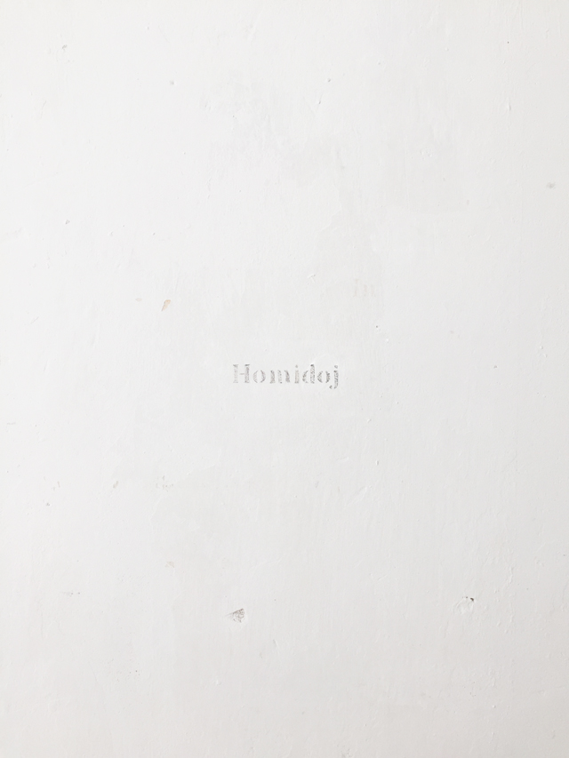 The words 'Homidoj' engraved on the wall