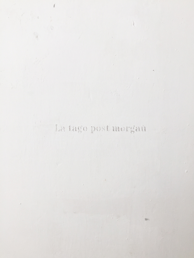 The words 'La tago post morgau' engraved on the wall